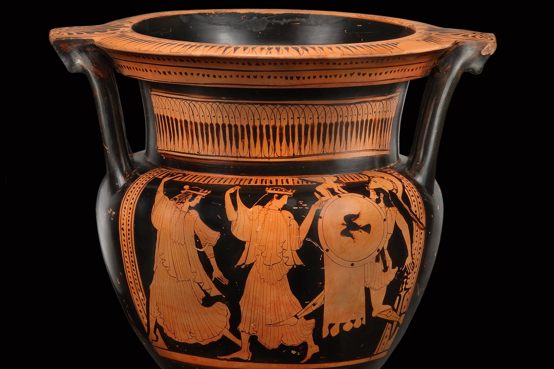 Photo: MUT Mixing vessel, red figures against black background, depicting two female figures running left, while turning their heads around to their backs, where an armed male figure is following them; a winged boy figure turns against the warrior and touches his shield