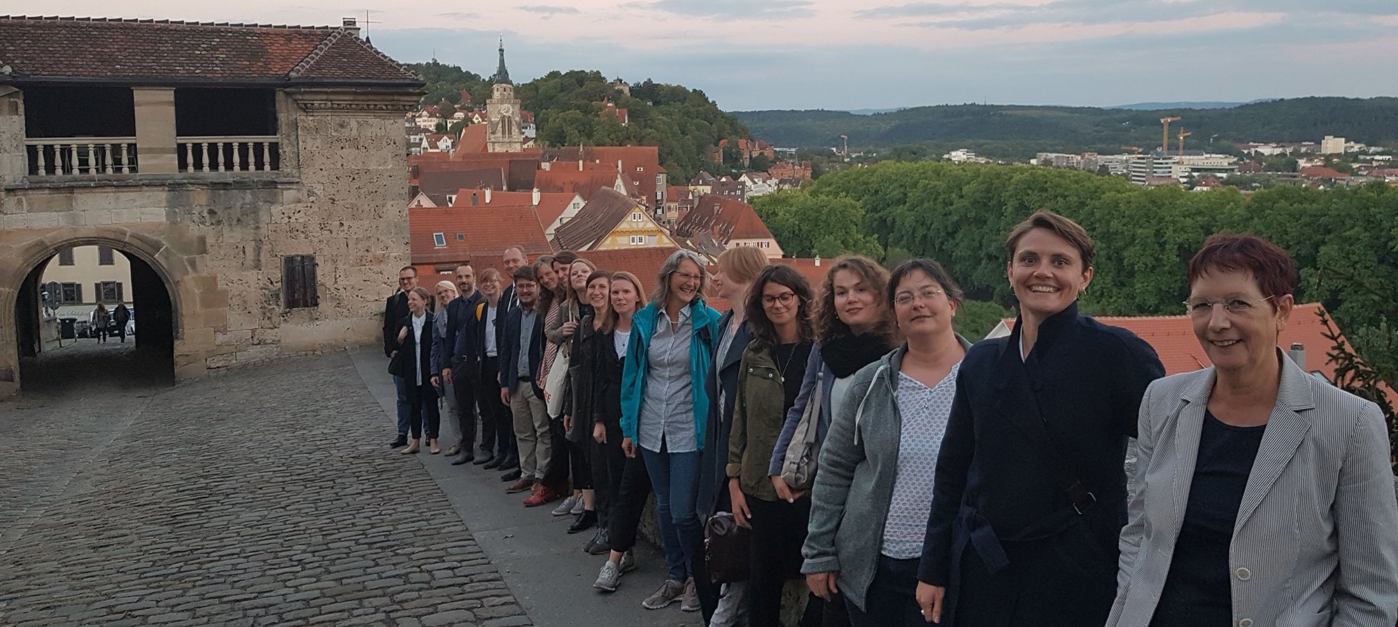 Die Teilnehmenden des Workshops stehen nebeneinander an der Mauer des Aufgangs zu Schloss Hohentübingen; im Hintergrund das Untere Schlosstor