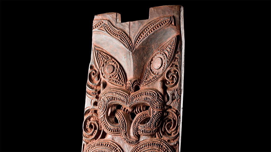 Kopfteil des geschnitzten, rotbraunen pou (Ahnenpaneel) der Hinematioro vor schwarzem Hintergrund