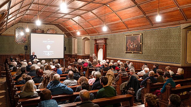 © MUT | Valentin Marquardt View of the castle church with a beamer and screen in front of the altar; at the lectern stands Prof. Dr. Ernst Seidl