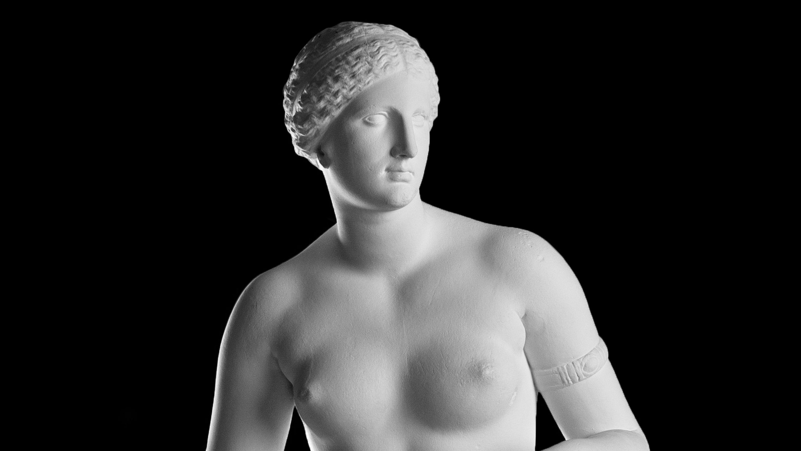 Bust detail of a photograph of a white moulding, depicting an naked Aphrodite with her head tilting to the right; she is wearing an armband on her left biceps