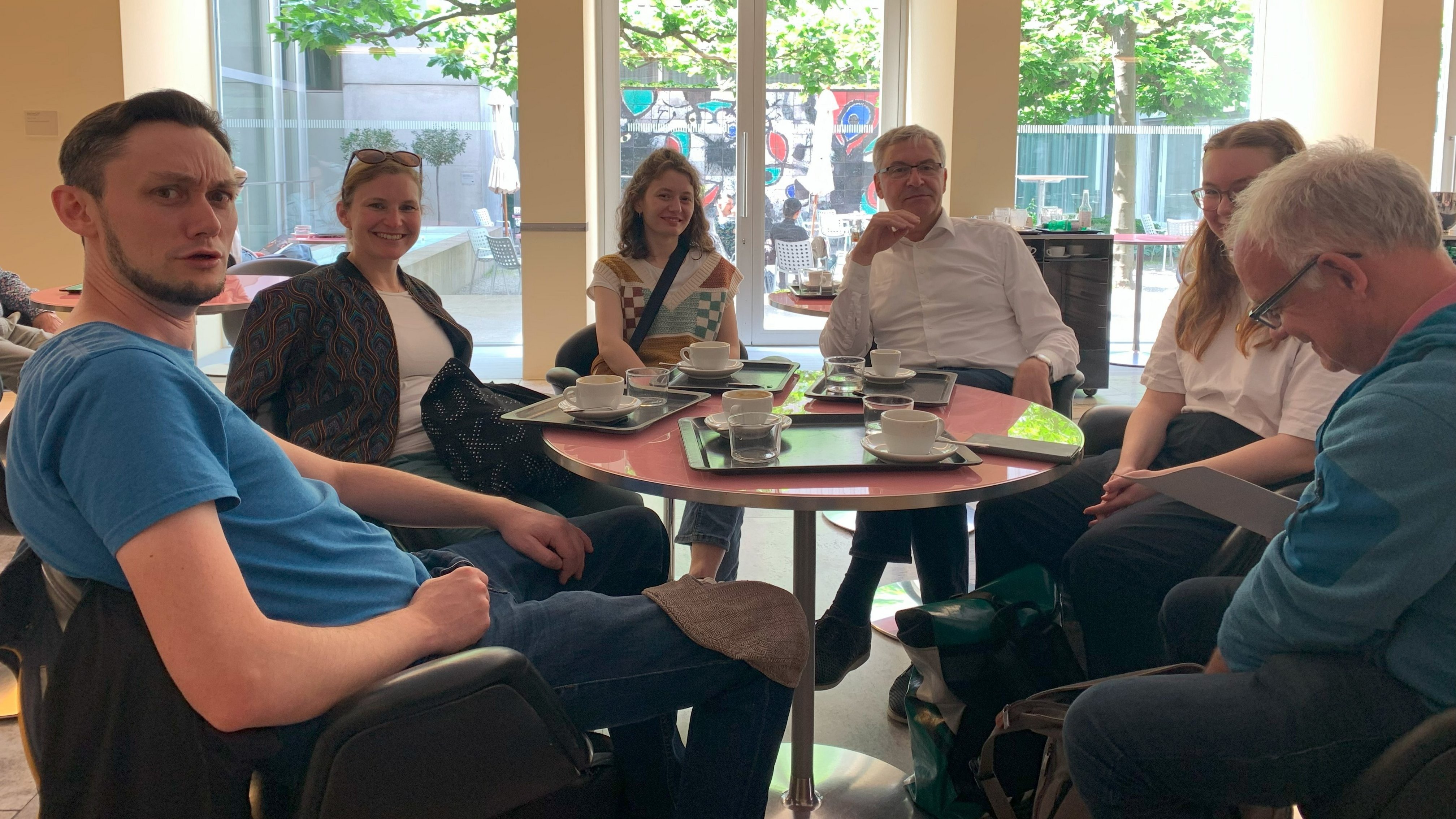 Auf dem Bild sind von links nach rechts einige der Mitarbeiterinnen und Mitarbeiter des MUTs an einem Café-Tisch zu sehen: Fabian Kurze, Annika Vosseler, Diellëza Hyseni, Ernst Seidl, Nele Morath und Edgar Bierende 