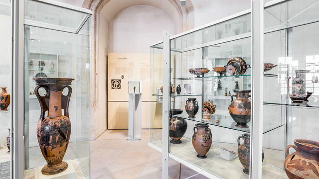 Foto: MUT | Valentin Marquardt Vitrinen mit griechischer Keramik im Rundturm im Museum Alte Kulturen und im Hintergrund der Waffenläufer in einer drehbaren Vitrine
