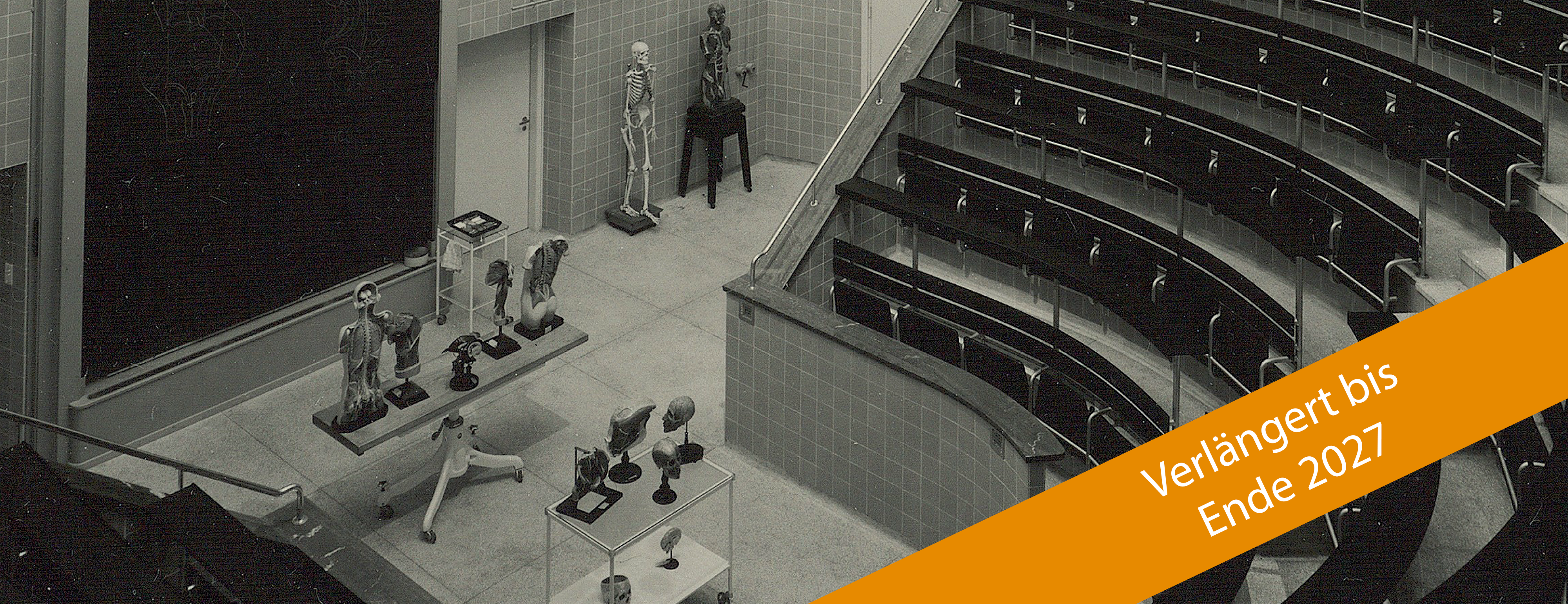 Schwarz-weißer Ausschnitt eines historischen Hörsaals mit Blick auf Präparate und unten rechts ein schräger Störer mit der Angabe "Verlängert bis Ende 2027"