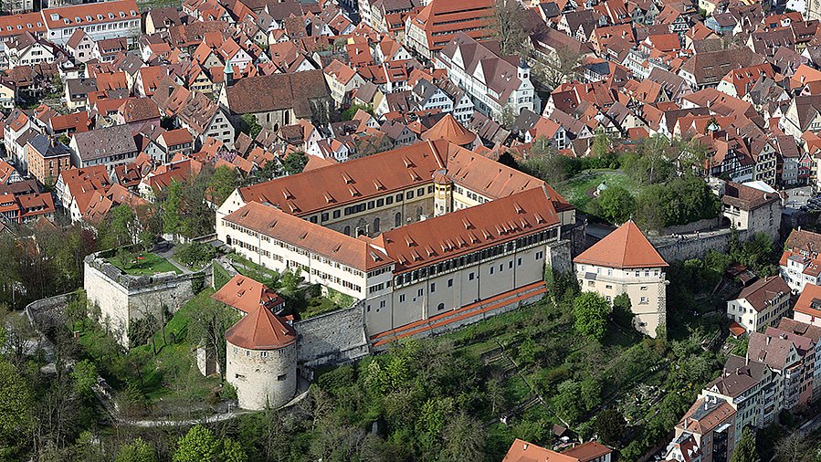 © MUT | Valentin Marquardt Aereal view of Hohentübingen Castle with greenery over the Castle Hill and the red roofs of Tübingen in the background