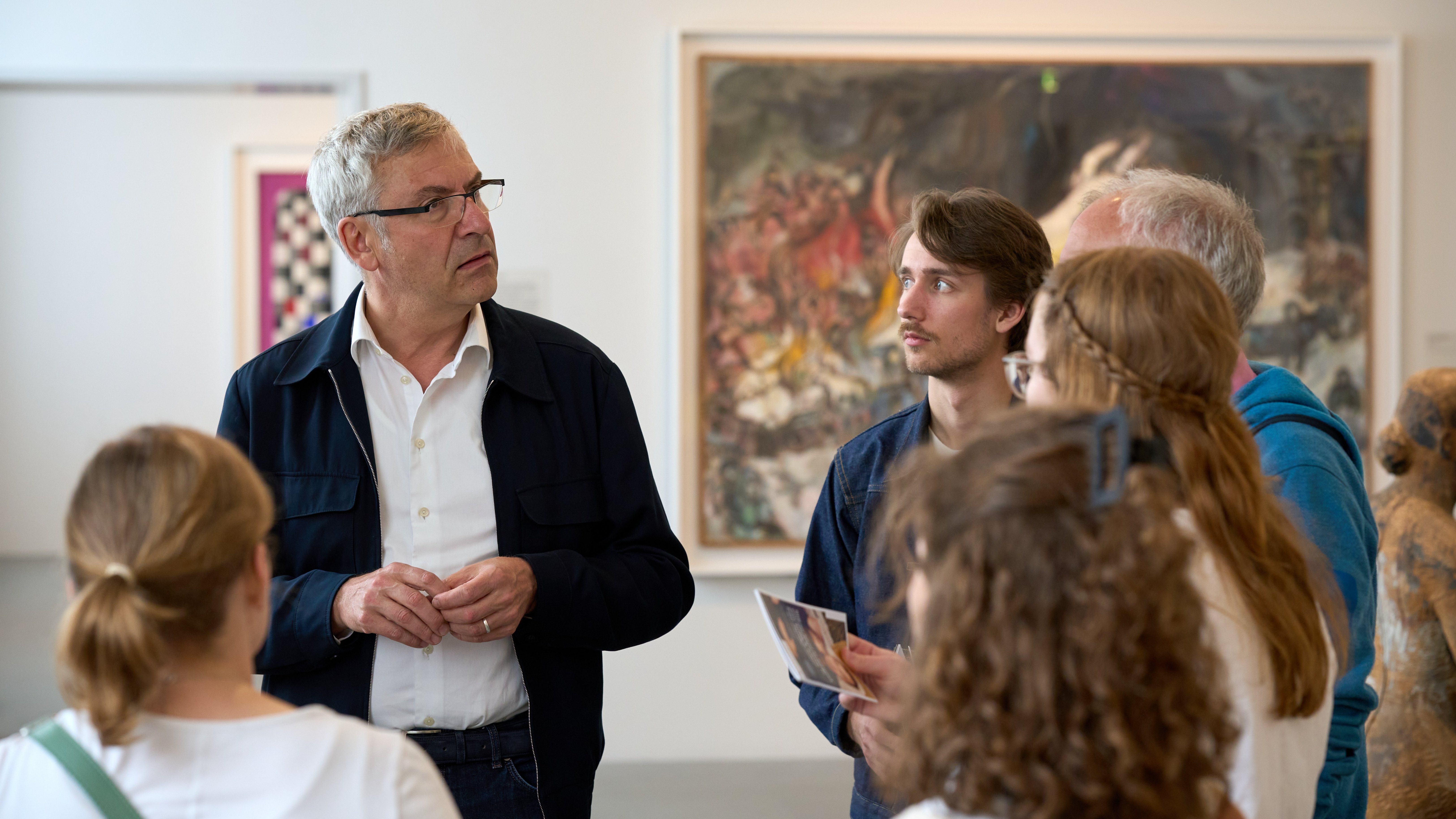 Zu sehen ist Ernst Seidl, der einigen Mitarbeiterinnen und Mitarbeitern im Kunsthaus Zürich etwas erklärt