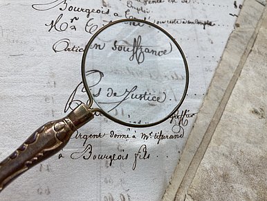 19th century document with magnifying glass showing the words "Souffrance" and "Justice © MUT | F. Huguenin