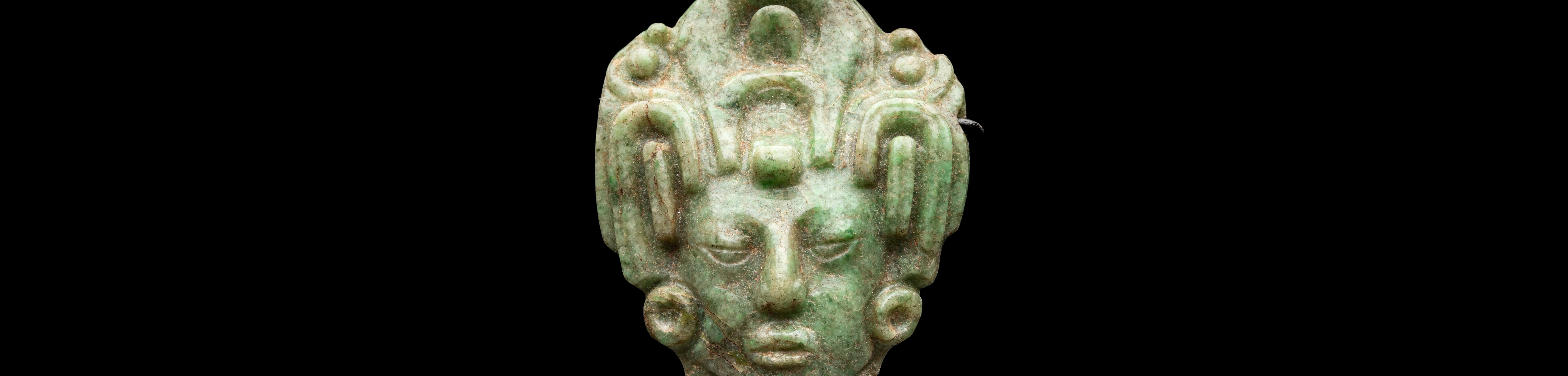 Central green jade head of a maize god against black background