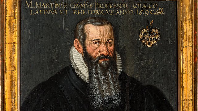 Gold gerahmtes, historisches Portrait von einem dunkel gekleideten Mann mit langem, grau-schwarzem Bart, der ein rotes Buch vor der Brust hält