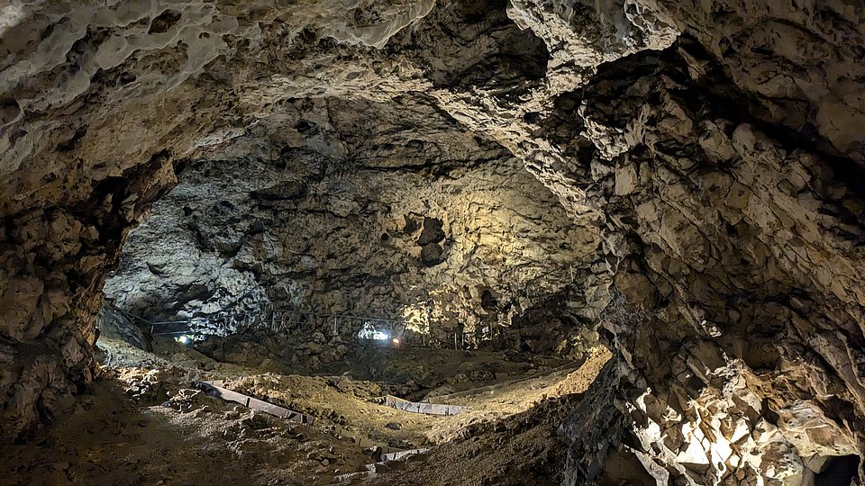 Ansicht der Hohle-Fels-Höhle mit kuppelartiger Decke, angeleuchtet von Grabungslampen, die in der Bildmitte platziert sind