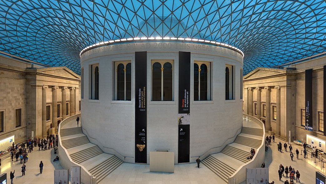 Atrium des British Museum in London mit zentralem Rundbau, an dem links und rechts je eine Treppe hinaufführt