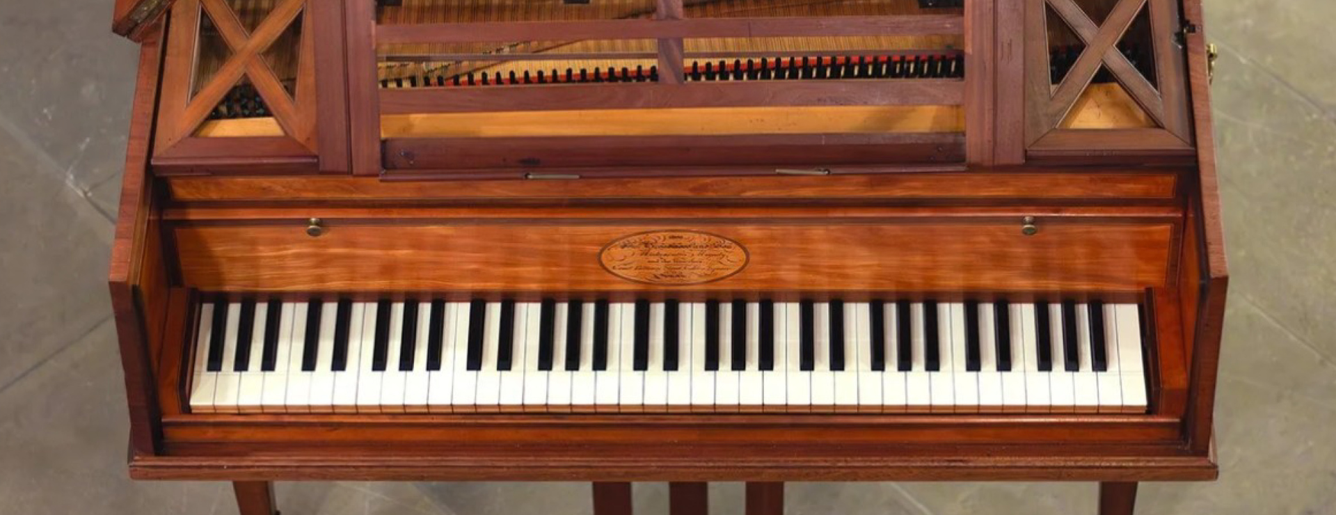 Draufsicht auf ein historisches Tasteninstrument aus rötlich-braunem Holz, Ausschnitt mit Fokus auf die Klaviatur